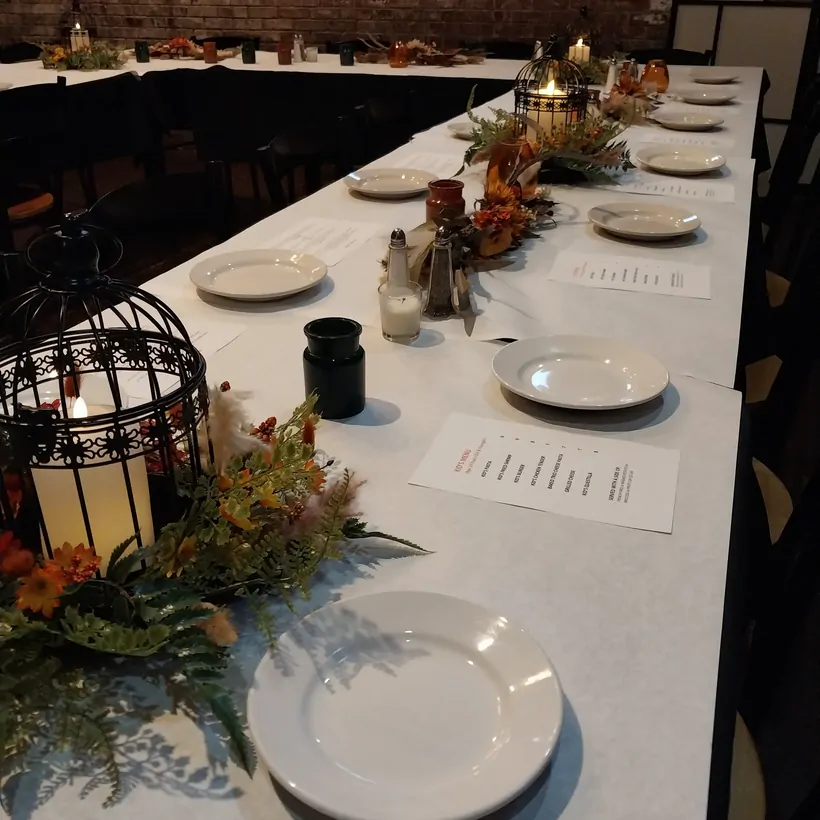 White-linen tables set with birdcage candle centerpieces against exposed brick at The Attic