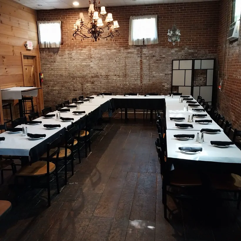 The Attic dining room with chandelier, exposed brick, and dark hardwood floors