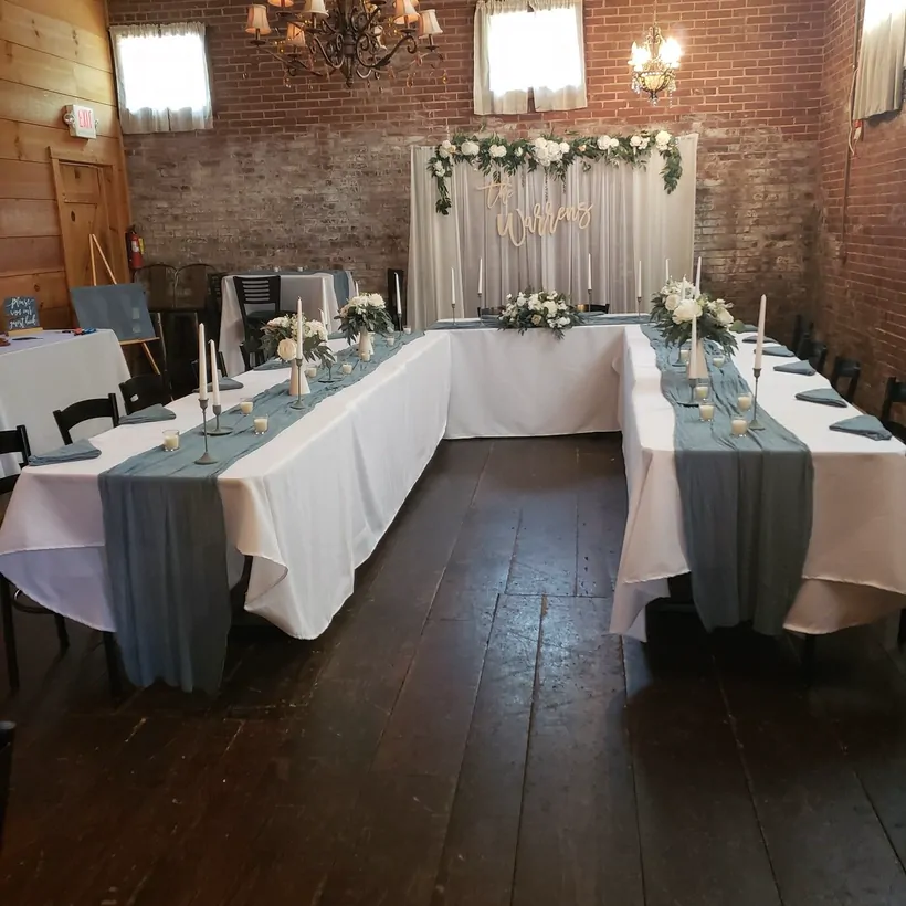 A wedding reception set up in the brick dining room at The Attic with floral backdrop