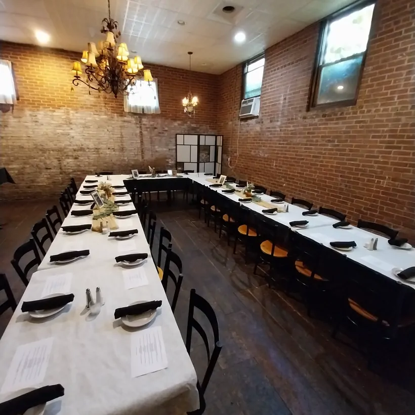 U-shaped banquet seating set with white linens under chandeliers at The Attic